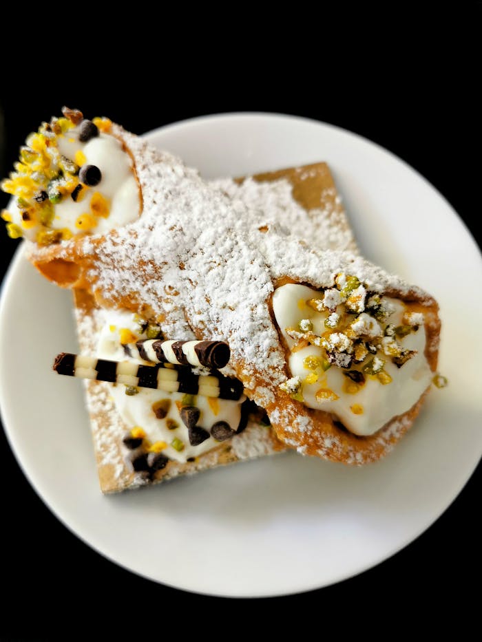 Appetizing close-up of traditional Sicilian cannoli topped with powdered sugar and creamy ricotta.